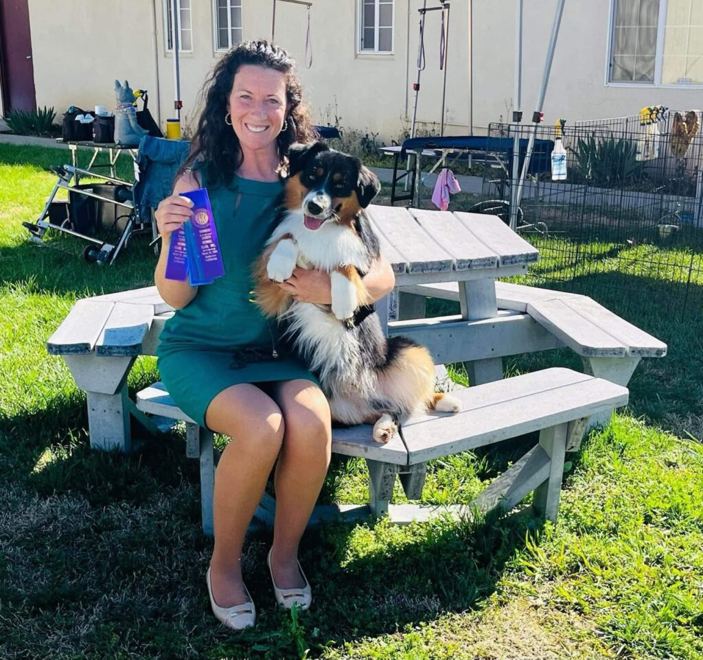 Laddie held up at a picnic table with his blue ribbons